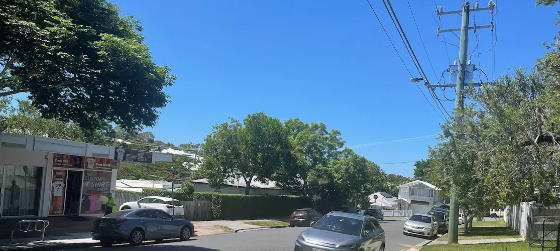 Street view showing the proximity of a retail shop to a nearby electricity transformer and overhead power lines in a Queensland residential area.